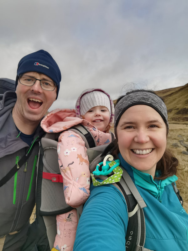 A family adventure! Phil and Cat with Maisie in the backpack on a hillside